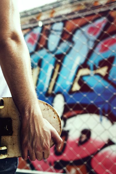 vista-traseira-closeup-de-braco-segurando-o-skate-com-fundo-de-parede-graffiti vista-traseira-closeup-de-braco-segurando-o-skate-com-fundo-de-parede-graffiti